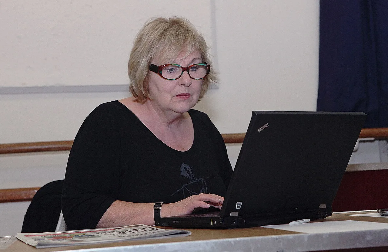 A woman using a laptop while comparing online choices
