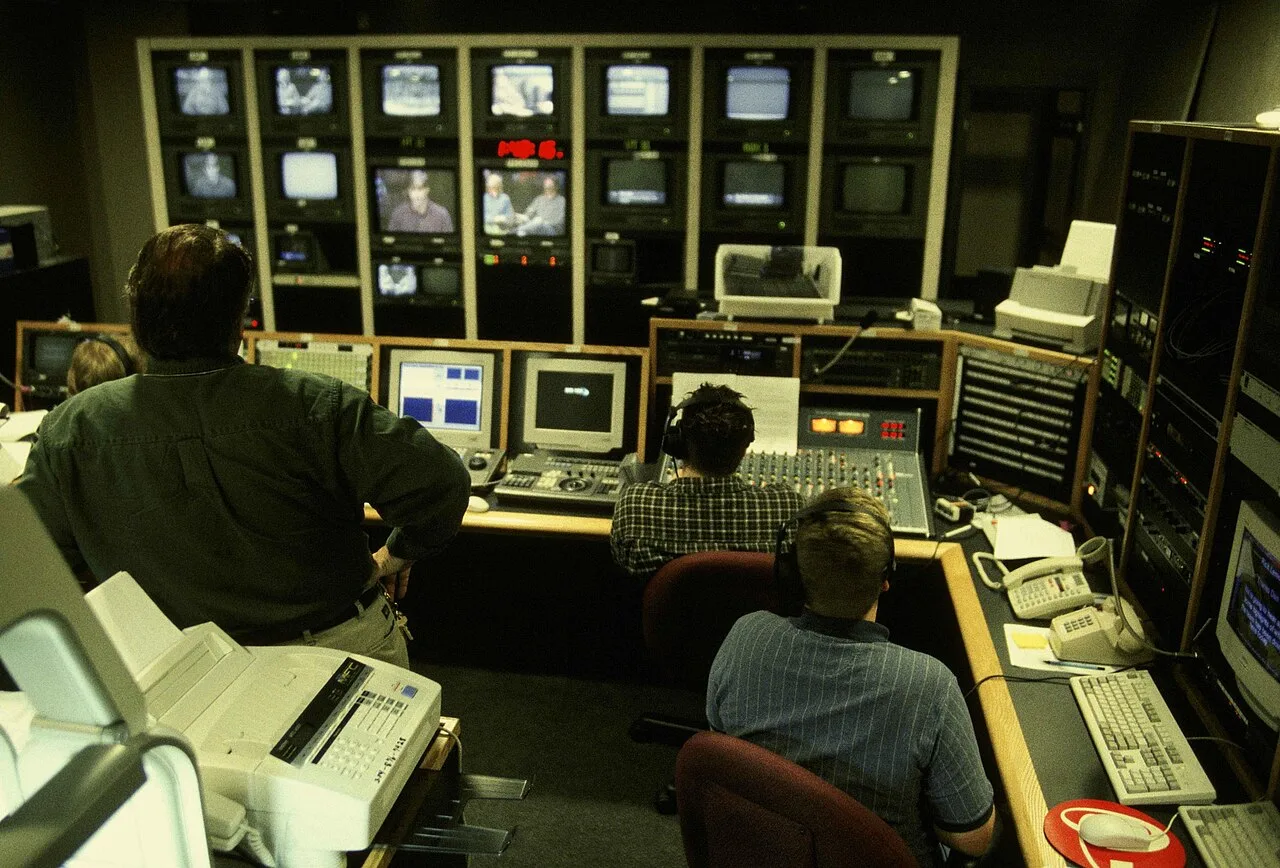 Video production workers comparing camera views on studio monitors